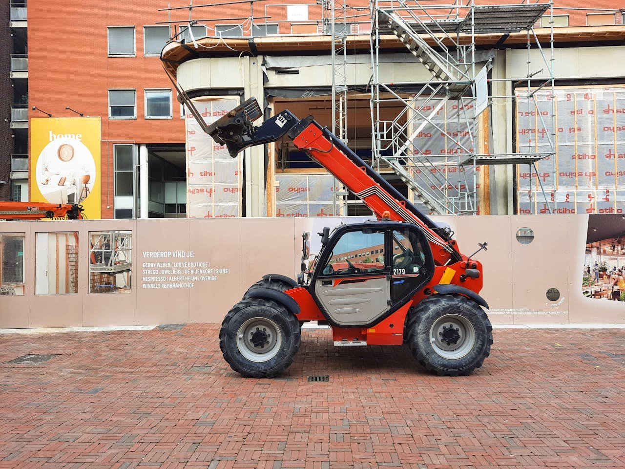 Crafting Captivating Headlines: Your awesome post title goes here A red telehandler parked at a construction site with scaffolding and building materials in the background.